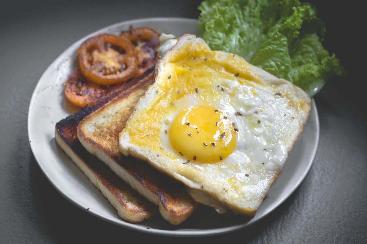 Sajian sarapan gourmet dengan telur, roti panggang dan kopi di teras Arunika.