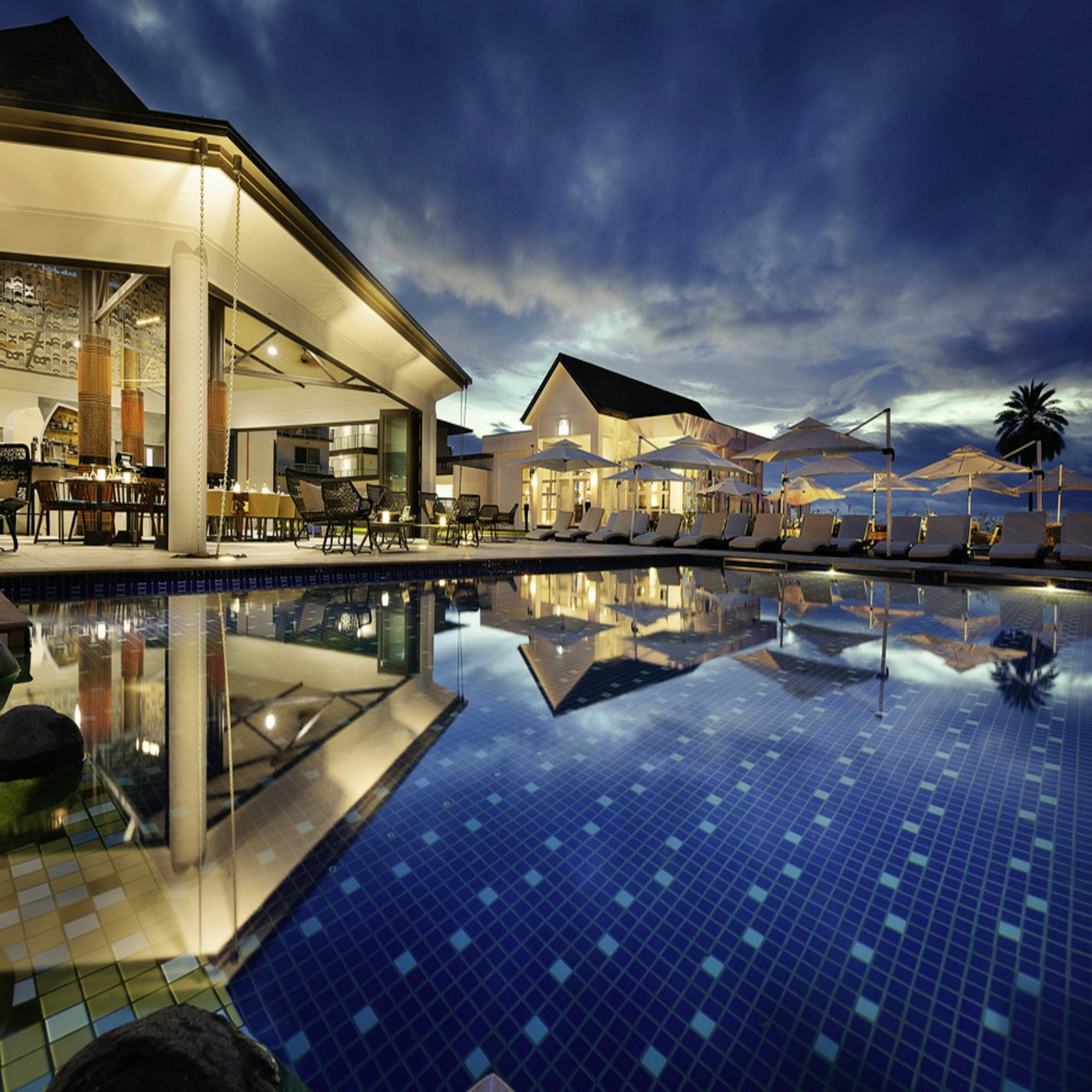 Kolam dan ruang makan hotel saat matahari terbenam.